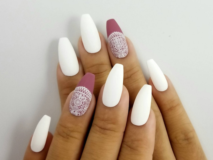 two hands with four visible fingers, and coffin shaped nails, three painted in matte white, and two in matte rose ash pink, with a white lace pattern