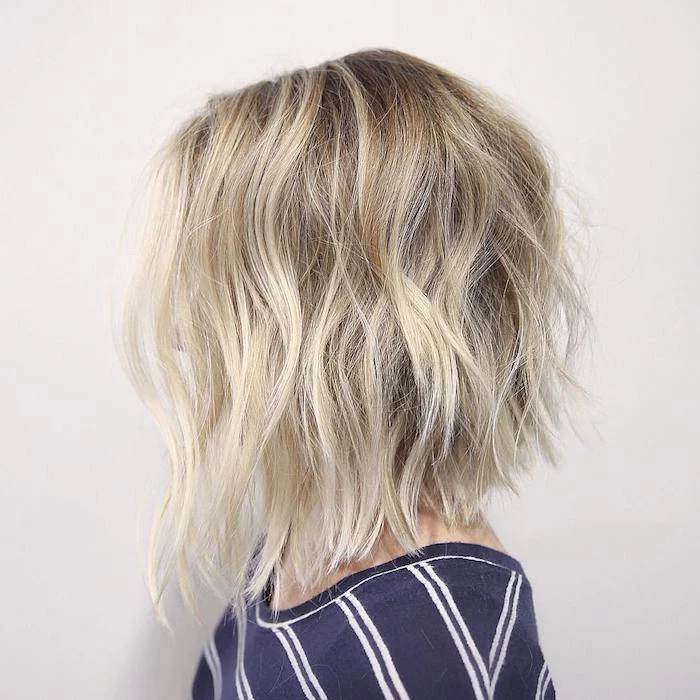 soft platinum blonde waves, on hair with dark ash blonde roots, hairstyles for women with thin hair, on woman in profile, wearing a striped jumper, with hair obscuring her face
