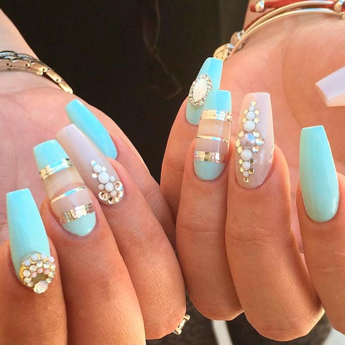 metallic silver stripes, rhinestones and clear details, decorating the turquoise blue, and nude pink nails of two hands, with folded fingers