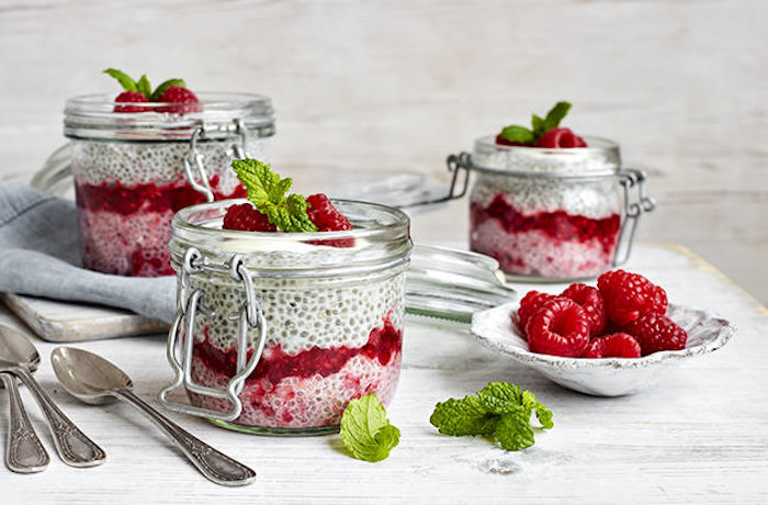 soaked seeds and yoghurt, with jam and raspberries, inside three snap lid jars, what is a healthy breakfast, topped with mint leaves
