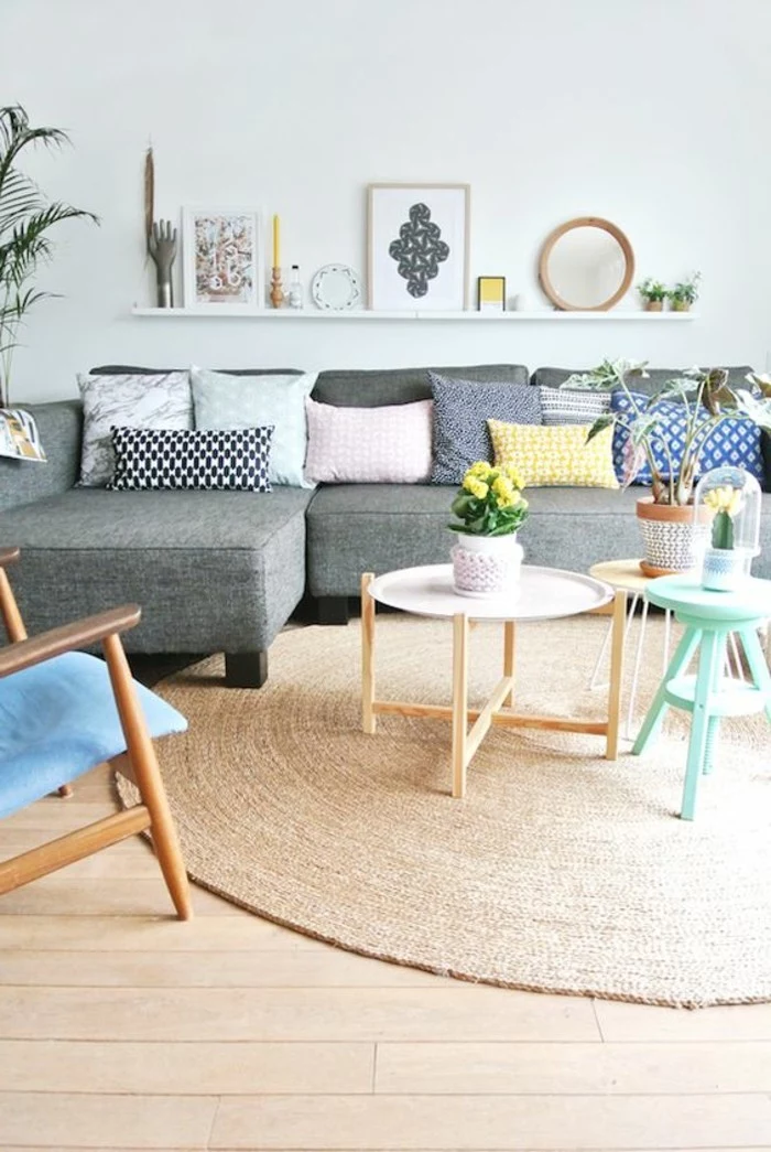 simple living room designs, bauhaus furniture inside a room, with duck's egg blue wall, grey corner sofa, with multicolored cushions, coffee tables and chairs 