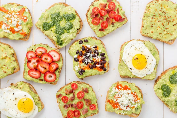 best breakfast for weight loss, twelve pieces of toast, with guacamole spread, and different toppings, strawberries and eggs, cherry tomatoes and beans