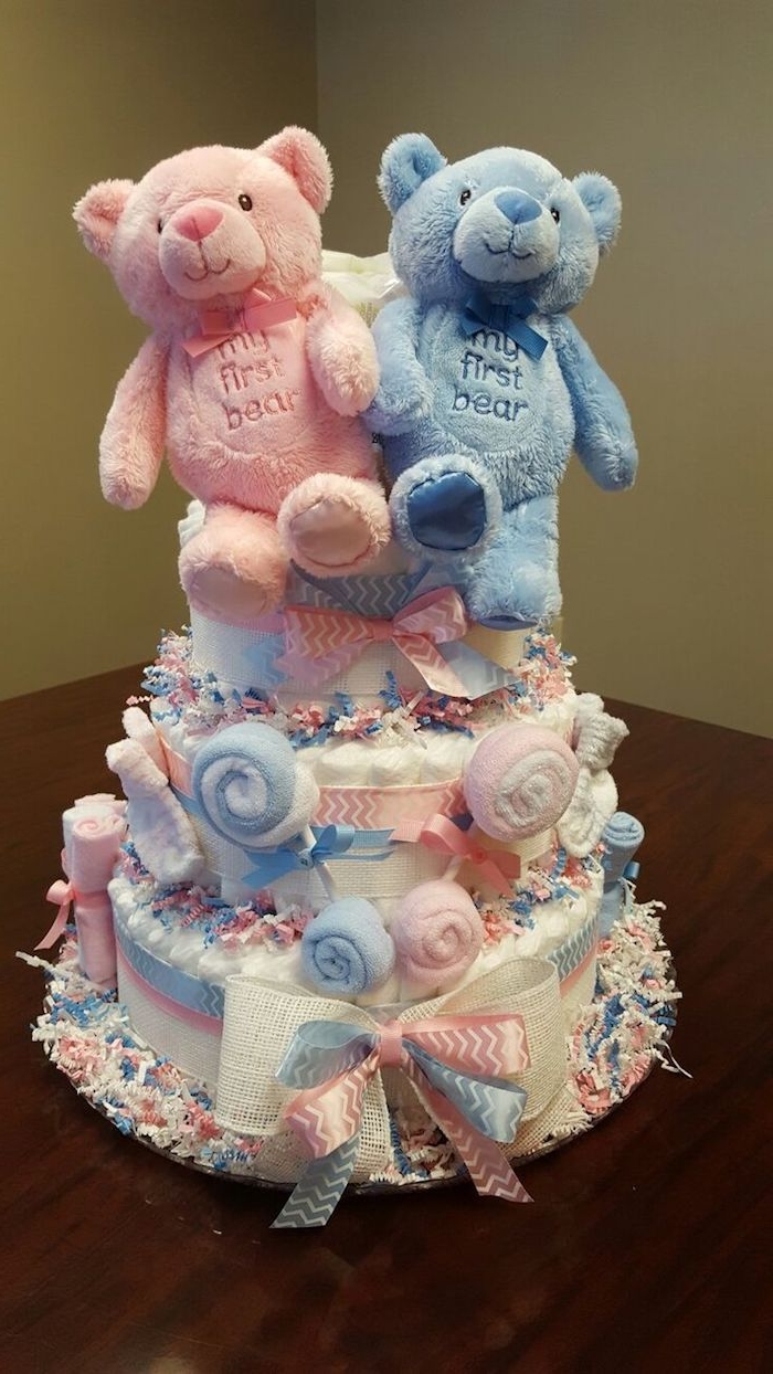 stuffed teddy bears, in pale pink and blue, with the words my first teddy, embroidered on their tummies, topping a diaper cake in pastel colors, twin baby shower cakes