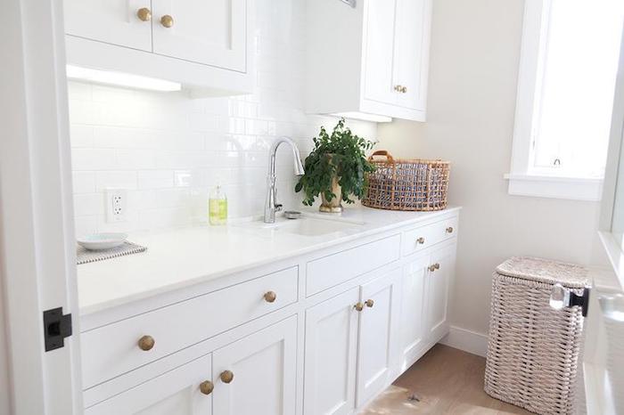 pure white subway tile pattern, glossy kitchen back splash, in a room with white cabinets, beige floor and a sink, large and small wicker baskets