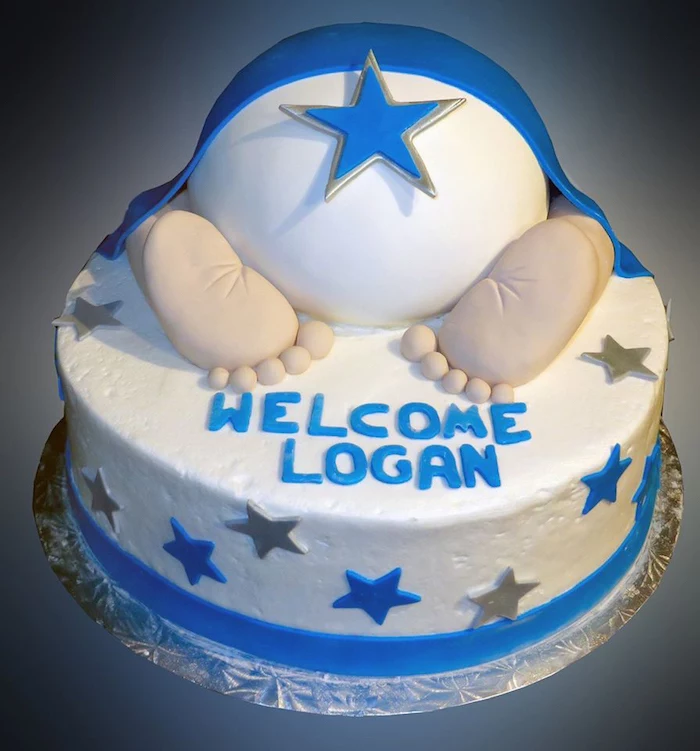 feet and nappy made from fondant, under a blue fondant blanket, topping a white cake, with a festive message, and blue and silver stars