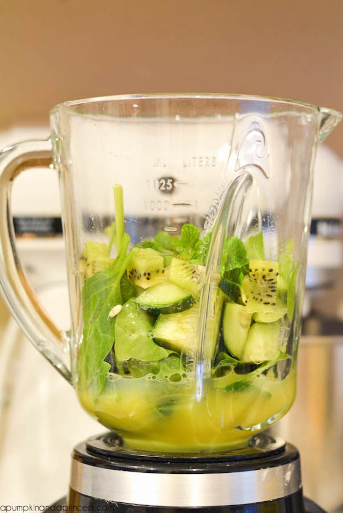 cucumber chunks and kiwi slices, spinach and mint leaves, inside the jug of a blender, healthy breakfast ideas, some yellow juice