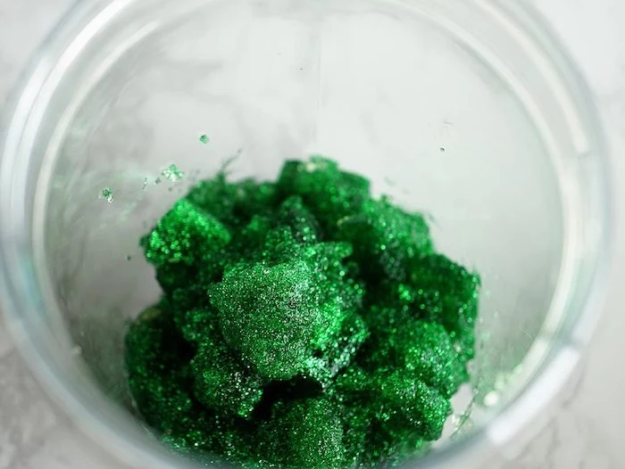 lumpy mix in a mossy gren color, how to make slime without borax, inside a narrow clear glass container, placed on a marble-like surface