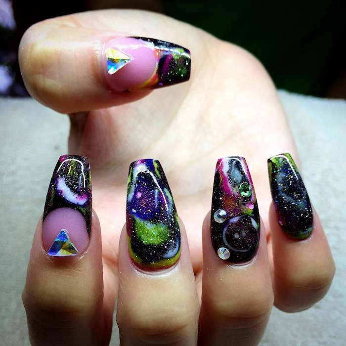 space-effect coffin nails, painted in pale pink, black and acid green, purple and white, and decorated with triangular, and round iridescent rhinestones