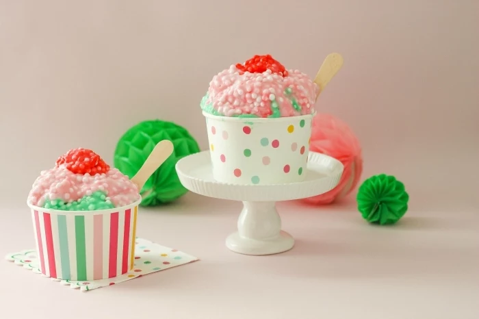 ice cream-like slime in red, green and pale pink, with small white beads, slime recipe with borax, poured into two multicolored paper cups