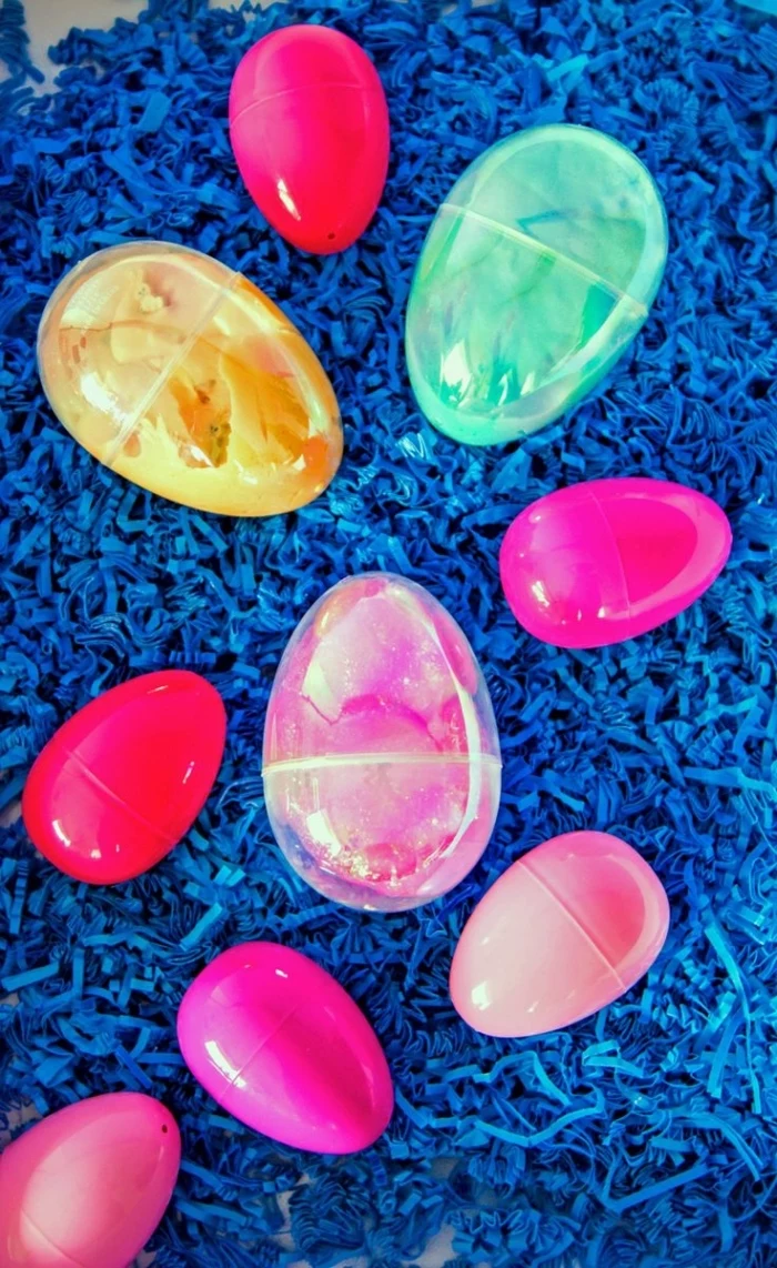 plastic easter eggs, six in different shades of pink, and three larger clear ones, all containing diy moulding goo, fluffy slime