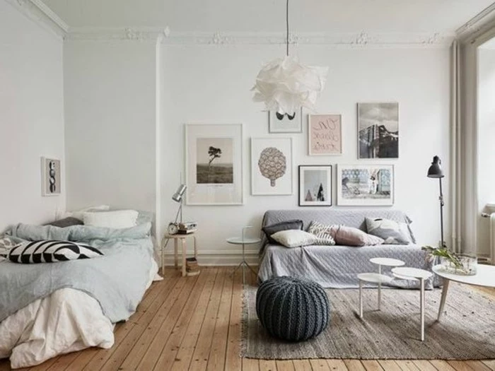 scandinavian style room, with a beige wooden floor, a bed in pale blue, sofa with a light lavender-colored cover, and several cushions, room setup ideas, framed artwork and coffee tables