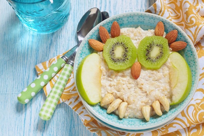 kiwi and green apple slices, cashew nuts and almonds, arranged on top of a bowl of porridge, to form an owl, what is a healthy breakfast, food for kids