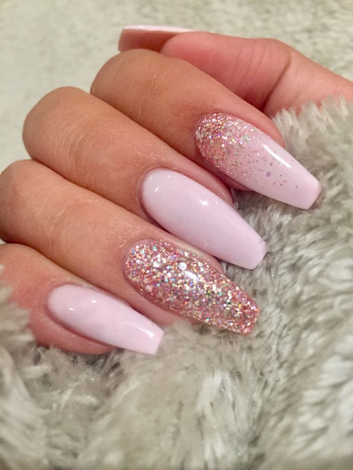 squoval nails in baby pink, decorated with pink glitter, and attached to a hand, gripping a light grey, fur-like fabric
