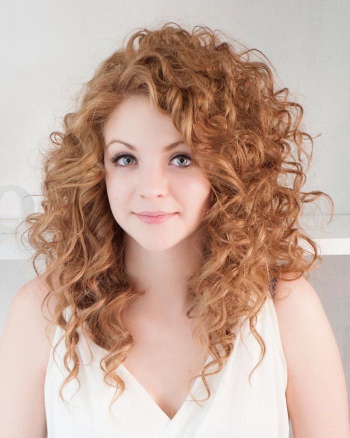 strawberry blonde woman, with medium long hair, curly with side part, wearing a white strappy top, and black eyeliner, haircuts for curly hair