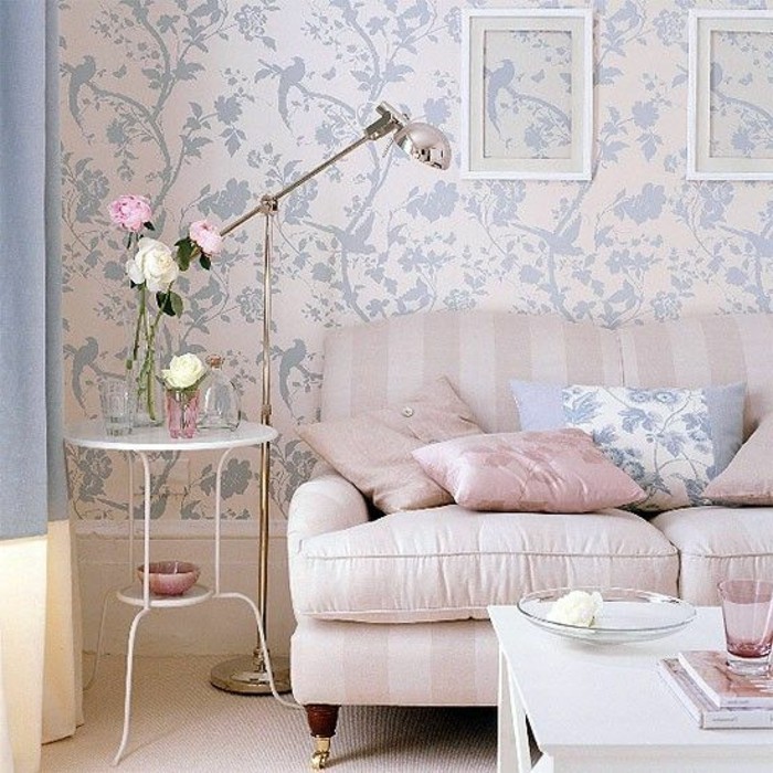 baby pink striped sofa, with matching pastel pink cushions, and one pale blue cushion, inside a room with light pink, and blue wallpaper, and two white coffee tables, in different sizes
