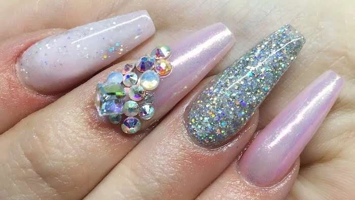 extreme close up, of four finger tips, with acrylic nail shapes, painted in milky pale pink nail polish, decorated with iridescent glitter, and pearly pink nail polish, decorated with rhinestones