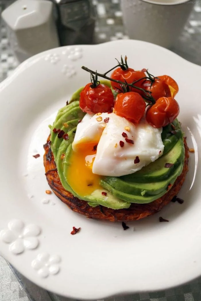 baked cherry tomatoes on the vine, on top of a poached egg, on a bed of avocado slices, low calorie breakfast, piece of toasted bread