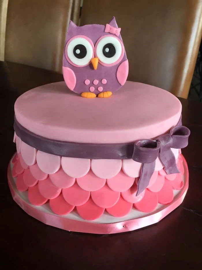 wide-eyed owl figurine, made from purple and pink fondant, with a little pink bow, topping a smooth cake, in four shades of pink, owl baby shower cake, dark purple fondant bow