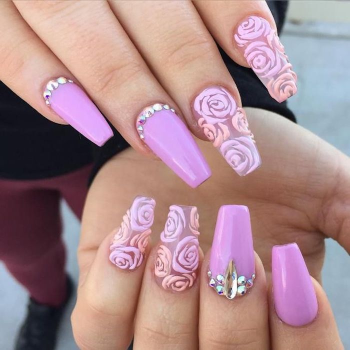 pink nails with rhinestones, and clear nails, decorated with rose drawings, in different shades of pink, with а ballerina nail shape, on two hands seen in close up