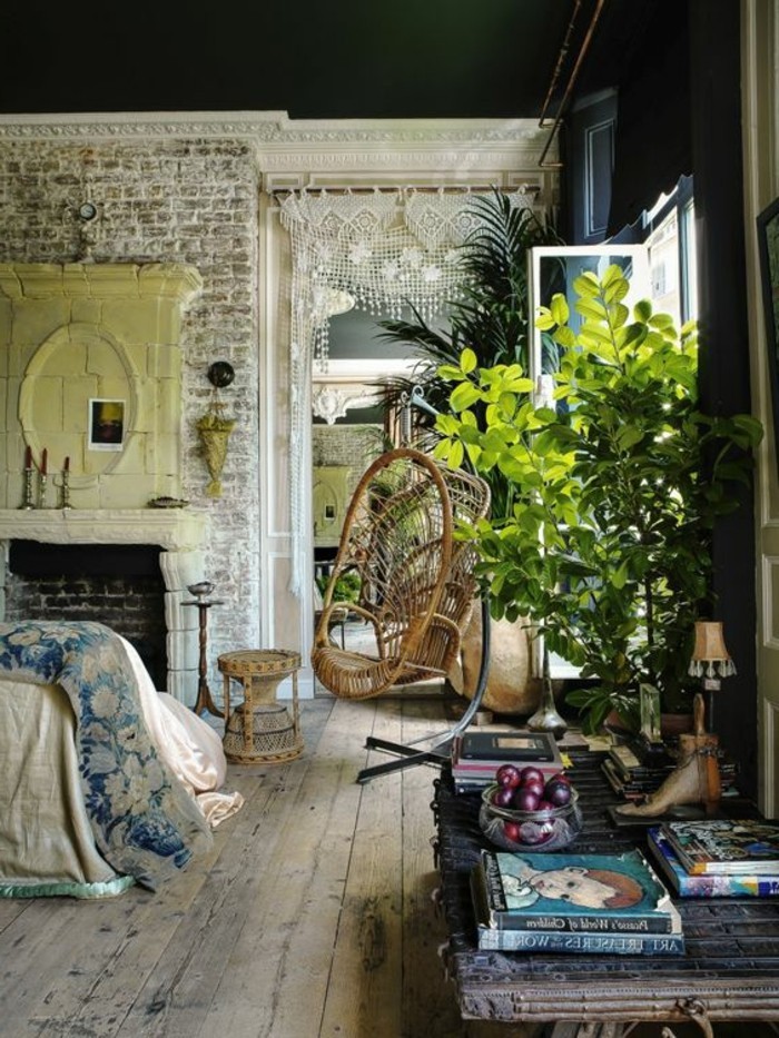 boho style rustic room, with a vintage and worn wooden floor, and shabby brick walls, large green indoor plants, books and decorations