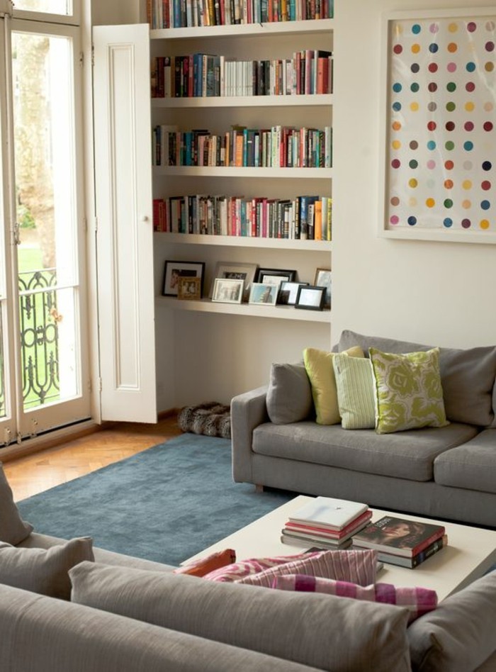 set of two pale grey sofas, with pink and yellow patterned cushions, a white coffee table, and white bookshelves, simple living room designs