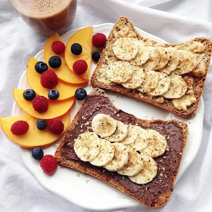 toast with different spreads, chocolate and peanut butter, topped with banana slices, cinnamon and sesame seeds, peach slices and berries