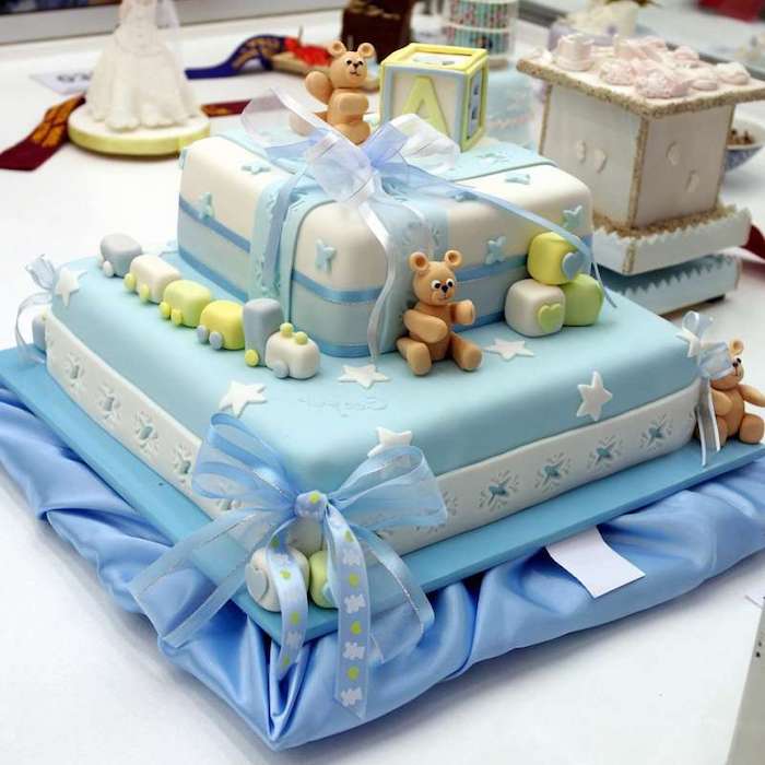 toy train and teddybears, and building blocks with letters and shapes, made from yellow and blue, green and white fondant, decorating a blue and white cake, with ribbons and bows