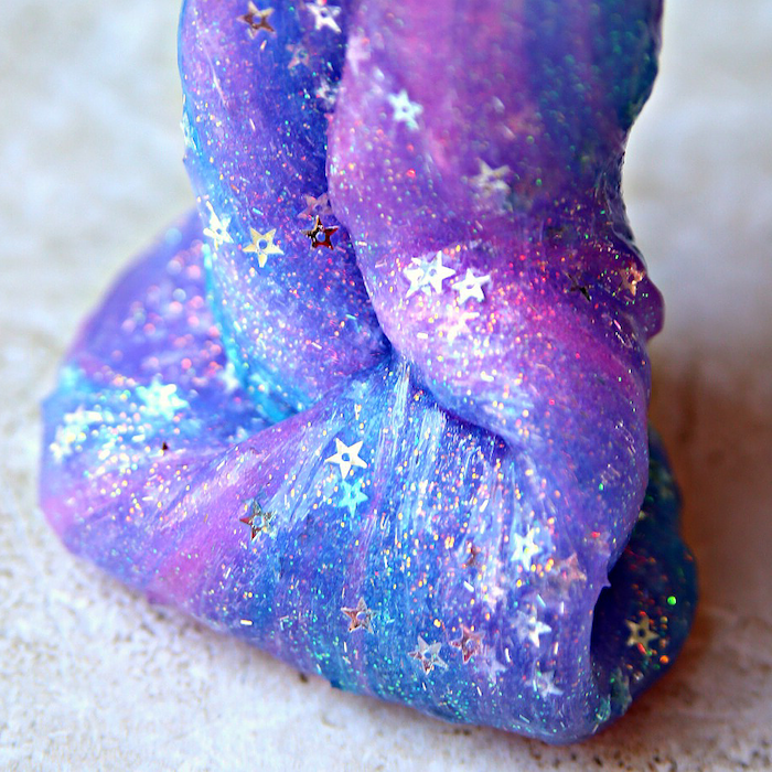 how to make slime with borax, blue and pink, galaxy-inspired goo, decorated with small silver stars, and fine glitter powder