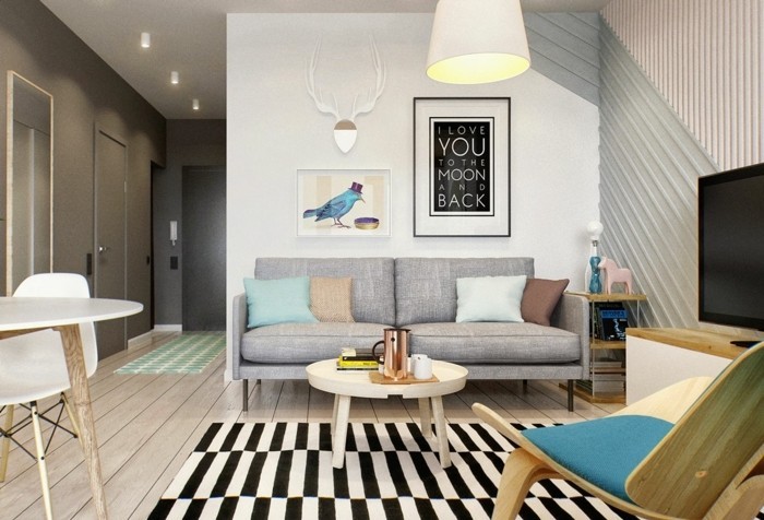 bauhaus style room, with a pale grey sofa, a striped black and white rug, and a small coffee table, how to decorate a living room, framed artwork and modern chairs