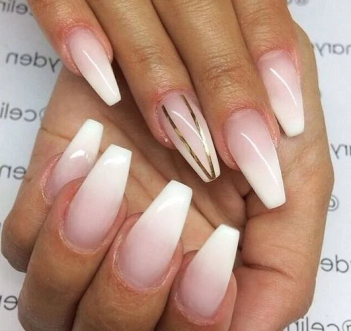 french-style ombre-effect nude coffin nails, with pale pink base, and white tips, one of the nails is decorated with two gold stripes