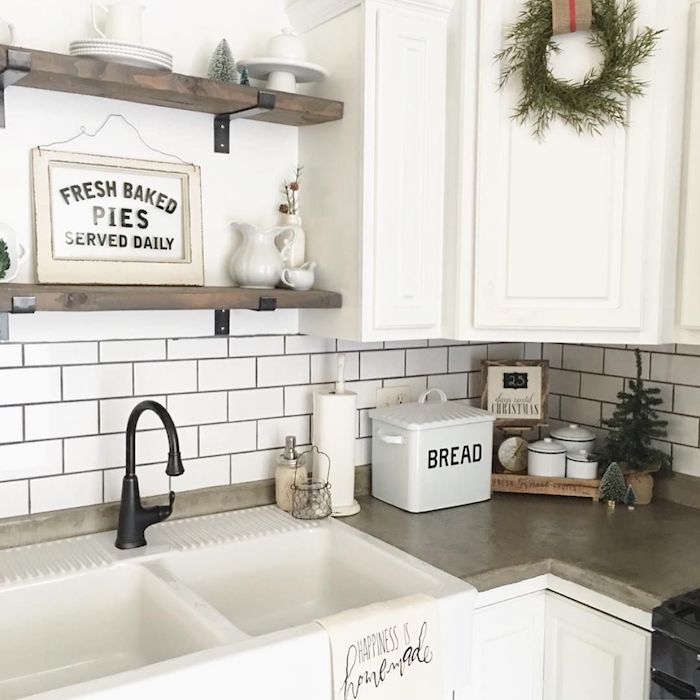 vintage style kitchen, with a beige counter top, retro-inspired white sink, and dark antique faucet, white subway tile pattern, and white cabinets