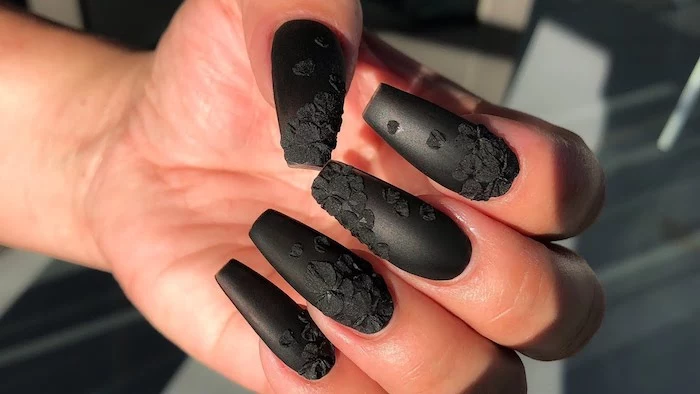 3D effect black acrylic flowers, decorating long nails, painted with black nail polish, coffin nail designs, on a hand with folded fingers