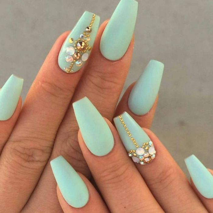 small gold beads, and iridescent rhinestones, on the ring finger nails, of two hands, with coffin manicure, painted in a pale turquoise color