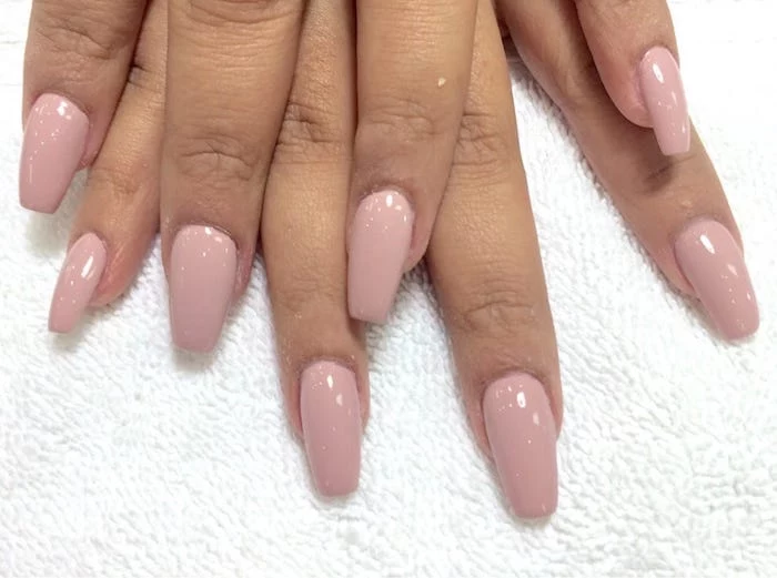 fabric in white, with towel-like texture, under eight tan fingers, oval nails with square tips, painted in nude pink nail polish
