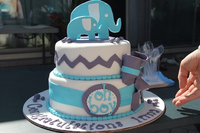 larger and smaller elephant figurines, made from blue and white fondant, topping a two-layered white cake, elephant baby shower cake, decorated with violet and blue details