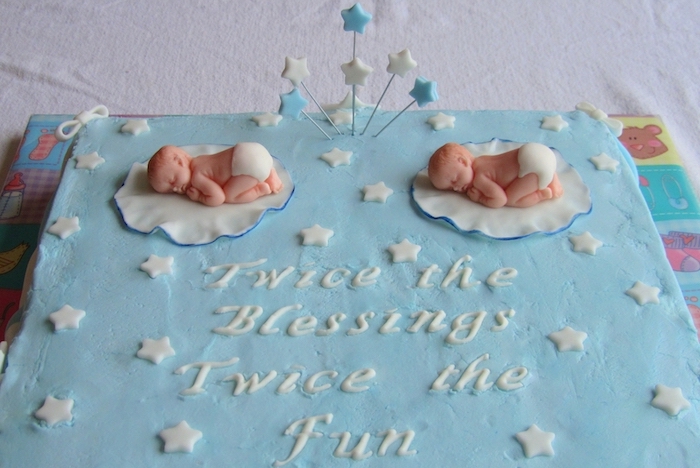 star shapes in blue and white, and two sleeping baby figurines, on a large square cake, baby shower sheet cakes, with a festive message