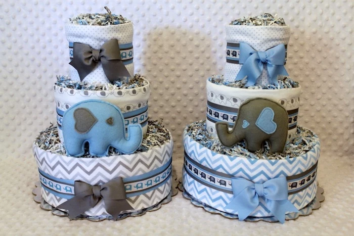 diaper cakes in white, with blue and grey patterns and bows, and two elephant stuffed toys, in blue and dark grey, elephant baby shower cake, a set of two