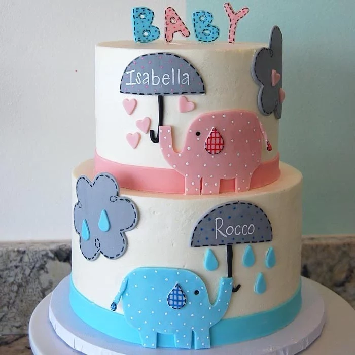 clouds and raindrops, decorating a white, two-layer cake, elephant baby shower cake, featuring a pink and a blue elephant, holding grey umbrellas, with the names rocco and isabella