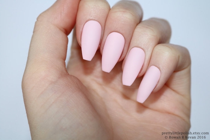 plain pale pink nail polish, on matte coffin nails, attached to a pale hand, with folded fingers, seen in close up