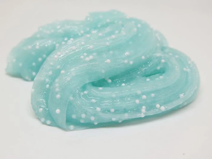 light teal colored gob of goo, decorated with tiny white beads, how to make slime with borax, twisted and slimy diy toy