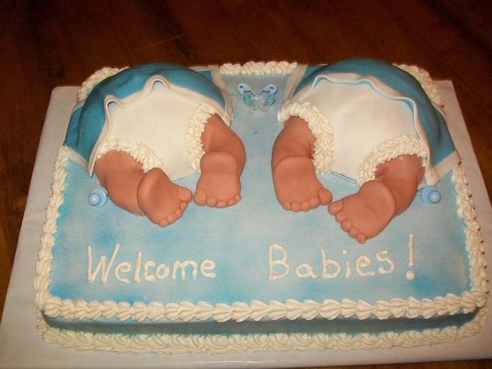tiny feet and white nappies, under two blue and white blankets, made from fondant, decorating a rectangular pale blue cake, twin baby shower cakes, with white frosting