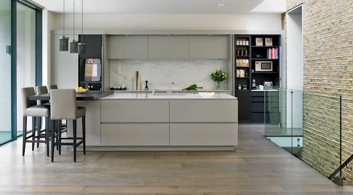 marble-like pale grey, and white kitchen backsplash, in a room with light grey cabinets, black shelves and a laminate floor