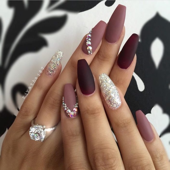 dark maroon and ashen rose matte nail polish, decorated with silver glitter and rhinestones, on the long nails of two hands 