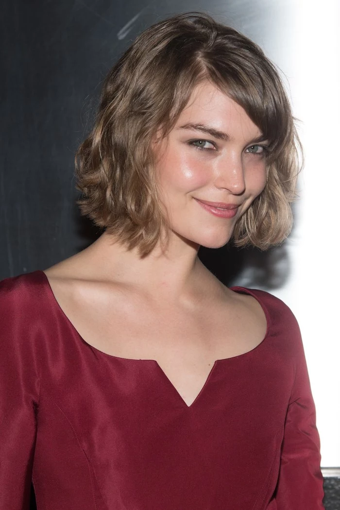 short hairstyles for fine hair, smiling brunette woman, wearing a long-sleeved silky wine red blouse, with wavy chestnut brown bob, and a side part