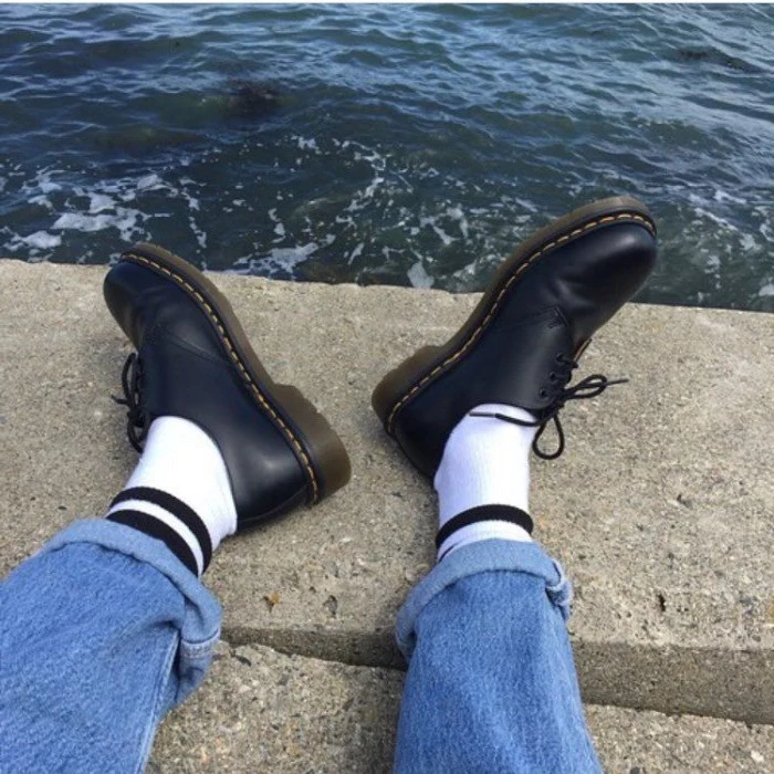 close up of black leather lace-up shoes, white socks with black stripes, and rolled-up retro jeans