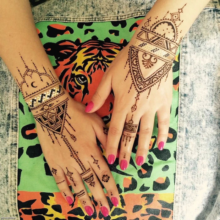 small henna tattoo, with delicate designs, featuring dots and lines, and muslim ornaments, on two hands, with pink nail polish