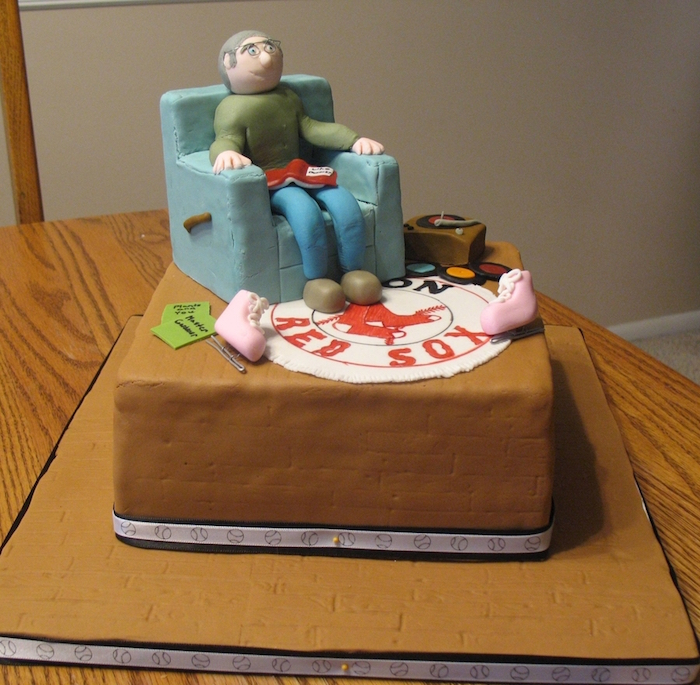 60th birthday party ideas for men, fondant figurine of a smiling man, sitting in a blue armchair, over a red sox logo carpet, surrounded by a vintage record player, and ice skates