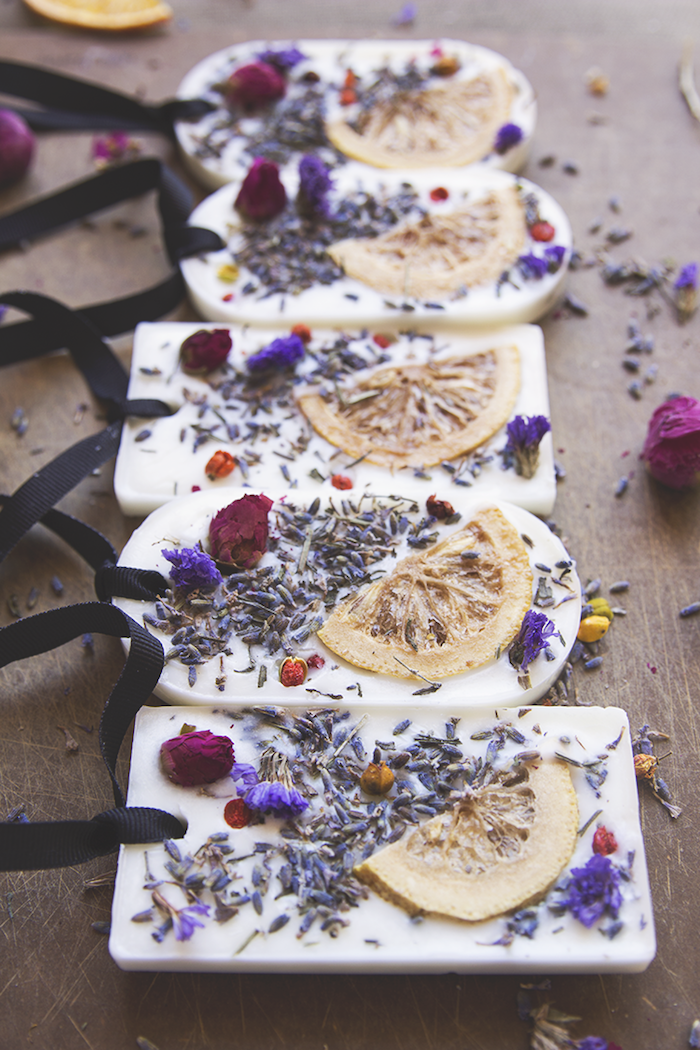 aromatic soaps with dried lemon slices and flowers in them, diy gift ideas, held with black ribbons, placed on wooden surface