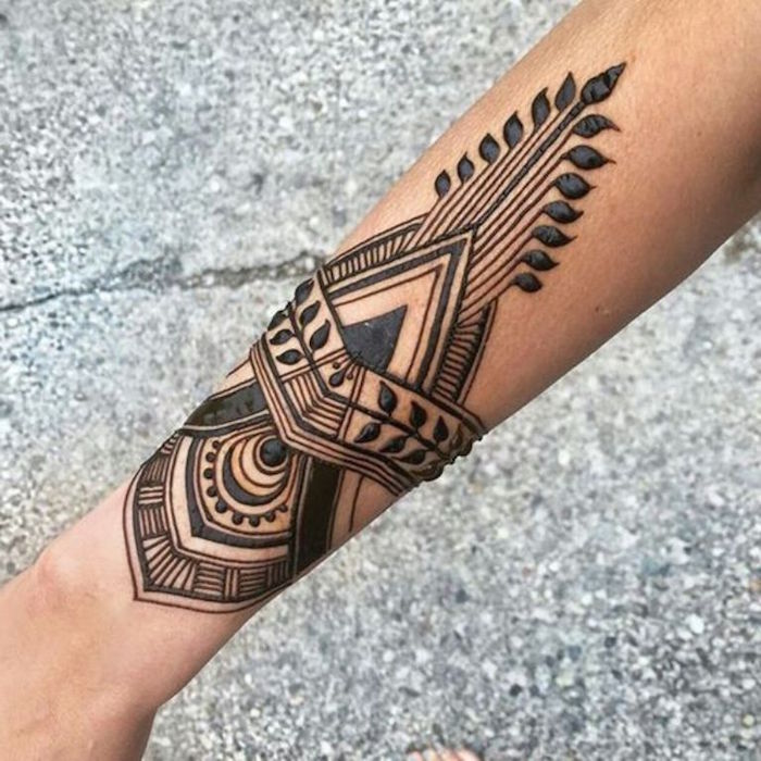 symmetrical art-deco-like henna tattoo, drawn in black, on a person's slim forearm