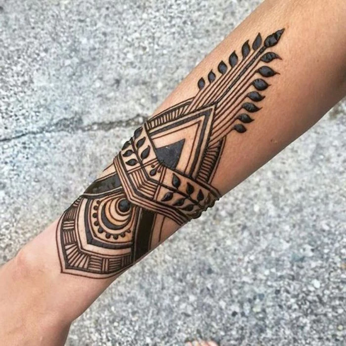 symmetrical art-deco-like henna tattoo, drawn in black, on a person's slim forearm